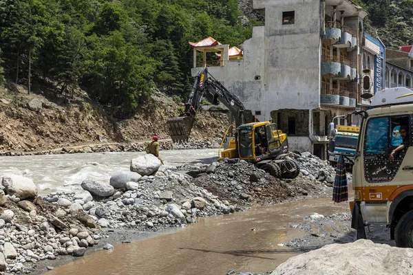 stock image Excavator working to protect the Bahrain bazar from the rising level of water in swat river at Bahrain : Bahrain swat, Pakistan - June 12, 2023.