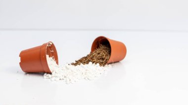 Toprak karışımı perlit ve hindistan cevizi coir tozu beyaz arka planda izole edilmiş küçük kaplarda karıştırılır.