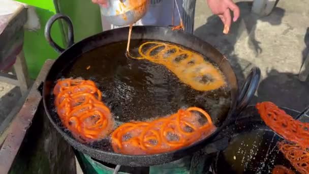ジャレビは南アジアで人気のスイートスナックです パキスタンのストリートフード市場で伝統的なスイートオレンジハラビスナックを作る — ストック動画