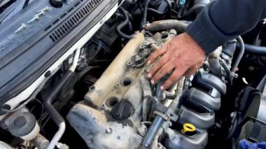 Otomatik mekanik bir araba motorunun ateşleme bobinini kuruyor ve kontrol ediyor