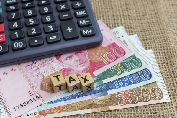 stock image Word Tax composed of wooden letters on a Pakistan banknotes with calculator. Tax concept.