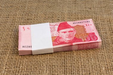 Stack of 100 Pakistani Rupees Banknotes on Burlap Surface clipart