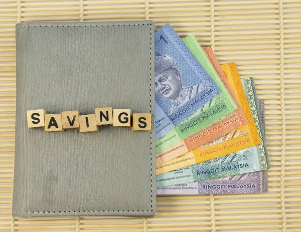 stock image SAVINGS text on a wooden blocks cubes on a wallet full with Malaysian Ringgit banknotes