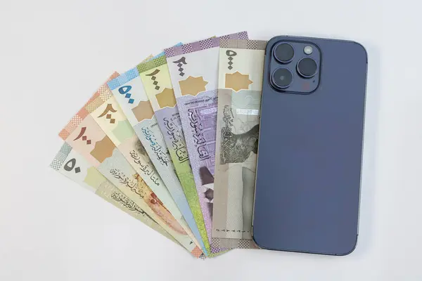 stock image Syrian currency notes with smartphone on white background. Mobile banking concept.