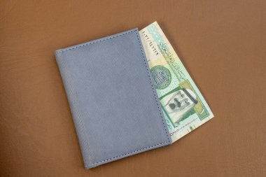 Saudi Riyal Currency in a Grey Wallet on a Leather Surface. Close-Up Shot. clipart