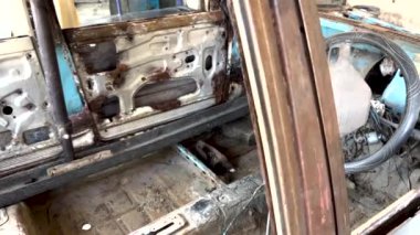 Atölyede restore edilen paslı, eski bir arabanın iç görüntüsü.