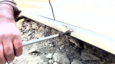 Araba tamircisi, göçük çıkarıyor. Profesyonel vücut onarımı. Otomobil tamircisi araba gövdesini ters çekiçle çekerek tamir etmiş..