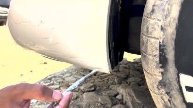 Boyacı arabanın ön tamponunu fırçayla çiziyor. Araba tamirhanesi.