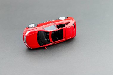 Gri arkaplanda ters dönmüş kırmızı oyuncak bir arabanın metin için kopyalama alanı ile yakın plan görüntüsü.