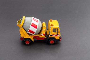 Gri arkaplanda kırmızı aksanlı sarı çimento karıştırıcı oyuncak kamyonu..