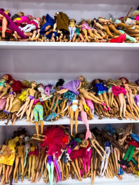 Shelves of mixed used dolls in a store clipart