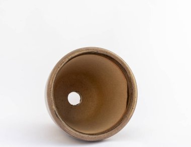 Boş seramik saksı beyaz arkaplanda izole edilmiş drenaj deliği gösteriyor