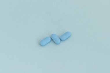 Closeup of a blue pills on blue background with copy space clipart