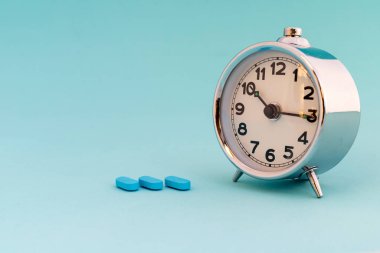 Alarm saatine yakın çekim ve minimalist arkaplanda mavi haplar