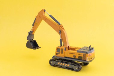 Oyuncak kazıcı ya da kazıcı sarı arka planda. Ağır inşaat aracı kavramı.