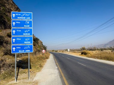 Directional road sign board in Swat valley, Pakistan. Swat valley tourist destination names written in urdu and english language clipart