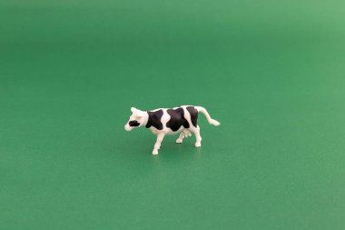 A single black and white plastic cow on green background clipart