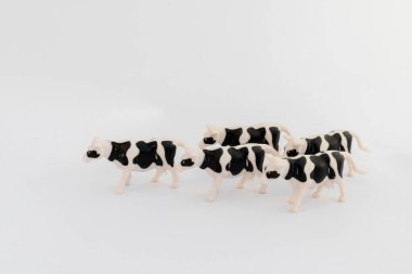 Beyaz arkaplanda siyah-beyaz plastik inek heykelcikleri grubu