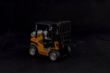 Siyah arkaplanda boş palet taşıyan minyatür forklift