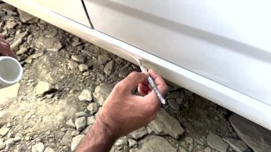 Arabanın gövdesi hasar görmüş. Araba gövdesini tamir eden boyacı, arabayı kazadan sonra fırçayla boyar..