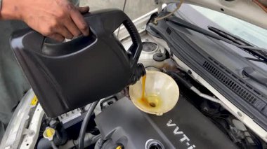 Bir huninin yardımıyla motora motor yağı dökülüyor. 4K video.