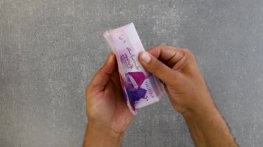 Tanınmayan el Pakistan 'da elli rupi para sayıyor. Elinde mor renkler olan elinle kapat. 50 rupi..