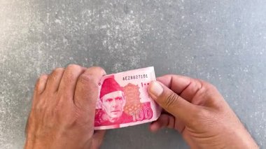 Pakistan 'daki adam 100 rupi sayıyor. Üst görünüm.