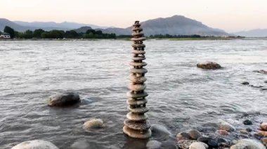 Nehir kıyısında dengelenmiş çakıl taşları. Meditasyon, uyum, sakinlik ve denge kavramı.