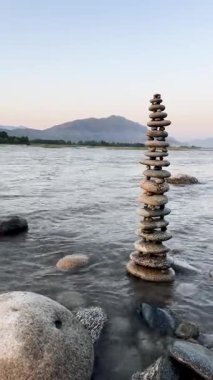 Arka planda nehir dağları ve gökyüzü olan taş piramit.