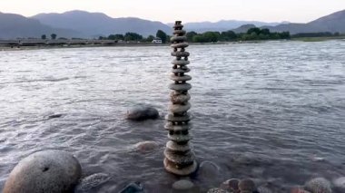 Gün batımında nehirde çakıl taşlarıyla dengelenmiş nehir taşları.