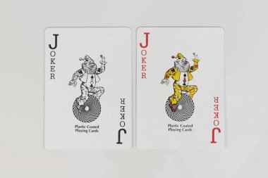 Beyaz arkaplanda siyah ve kırmızı kart oynayan Joker yan yana klasik güverte çifti