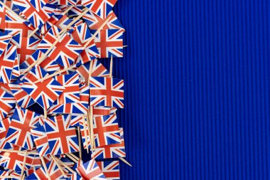 Mavi dokulu arka planda Birleşik Krallık 'ın küçük kağıt bayrakları. Metin için boş boşluk.