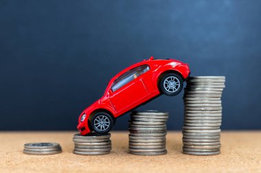 Kırmızı Oyuncak Araba Bozuk Para Yığını. Benzin ve Otomobillerin Giderek Düşen Maliyetini Sembolize Ediyor.