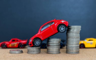 Bozuk para yığınından yokuş aşağı inen oyuncak arabalar. Fiyat veya Maliyet Düşüşü Konsepti