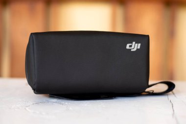 DJI, Omuz Kayışlı Koruyucu Taşıma Davasını Tahta Masa Üzerinde Bulanık Arkaplan ile Damgaladı