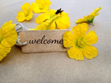 Sarı çiçekli bir karton etikete hoş geldiniz. Hoş geldiniz işareti arka planı.