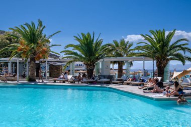 Ios, Yunanistan - 6 Eylül 2022: Genç turistler Yunanistan 'daki ünlü Mylopotas plajı önünde açık havuzun keyfini çıkarıyorlar