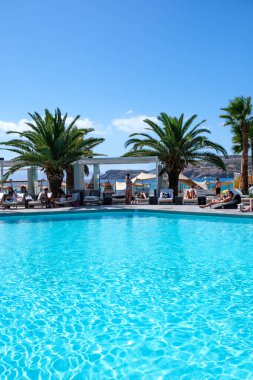 Ios, Yunanistan - 6 Eylül 2022: Genç turistler Yunanistan 'daki ünlü Mylopotas plajı önünde açık havuzun keyfini çıkarıyorlar