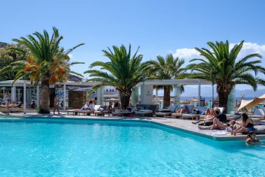 Ios, Yunanistan - 6 Eylül 2022: Genç turistler Yunanistan 'daki ünlü Mylopotas plajı önünde açık havuzun keyfini çıkarıyorlar