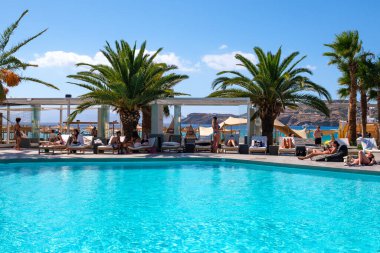 Ios, Yunanistan - 6 Eylül 2022: Genç turistler Yunanistan 'daki ünlü Mylopotas plajı önünde açık havuzun keyfini çıkarıyorlar