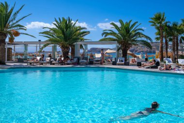 Ios, Yunanistan - 6 Eylül 2022: Genç turistler Yunanistan 'daki ünlü Mylopotas plajı önünde açık havuzun keyfini çıkarıyorlar