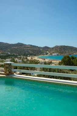 Ios, Yunanistan - 6 Eylül 2022: Yunanistan 'daki ünlü Mylopotas plajına bakan güzel bir yüzme havuzu manzarası