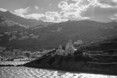 Kilisenin panoramik manzarası Agia Irini, liman ve Ios Yunanistan köyü güneş doğarken siyah beyaz