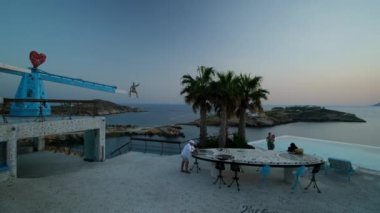 Ios, Yunanistan - 10 Eylül 2022: İçkiler, kokteyller ve Ios Yunanistan 'daki Pathos lounge bar restoranında muhteşem bir günbatımı yaşayan turistler