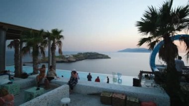 Ios, Yunanistan - 10 Eylül 2022: İçkiler, kokteyller ve Ios Yunanistan 'daki Pathos lounge bar restoranında muhteşem bir günbatımı yaşayan turistler