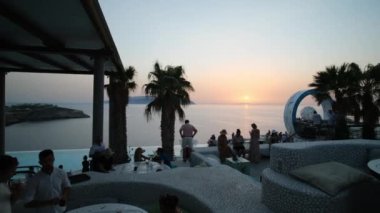 Ios, Yunanistan - 10 Eylül 2022: İçkiler, kokteyller ve Ios Yunanistan 'daki Pathos lounge bar restoranında muhteşem bir günbatımı yaşayan turistler