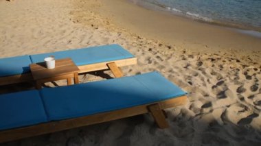 Ios, Yunanistan - 11 Eylül 2022: İki lüks güneş yatağı ve Yunanistan 'daki güzel ve ünlü Mylopotas plajının panoramik manzarası