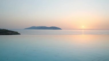 Ios, Yunanistan - 10 Eylül 2022: Ege Denizi manzaralı güzel büyük yüzme havuzu Ios 'taki Pathos bar ve Restoran' da güneş batarken