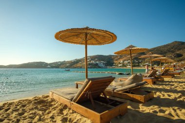 Ios, Yunanistan - 8 Eylül 2022: Güneş yatakları, güneş şemsiyeleri ve Yunanistan 'ın güzel kumlu Mylopotas plajının panoramik manzarası