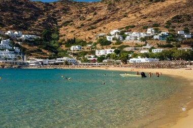 Ios, Yunanistan - 15 Eylül 2022: Yunanistan 'daki güzel Mylopotas plajı boyunca yürüyen turistler